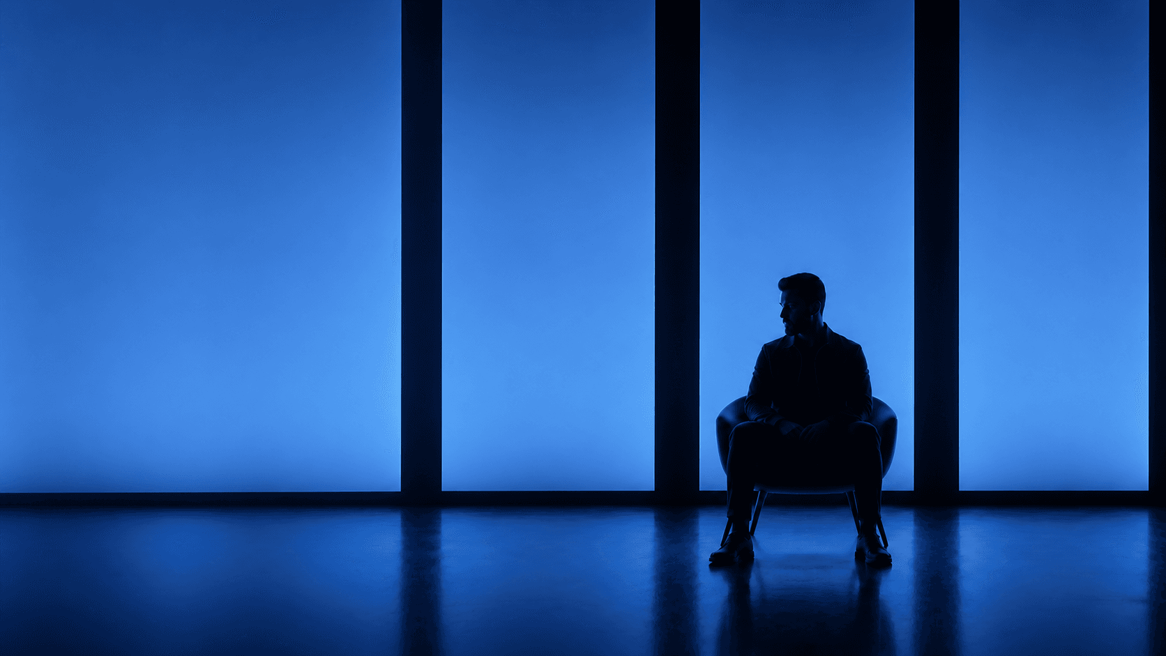 Ayaan Saeed seated in silhouette against illuminated Praxum-blue panels