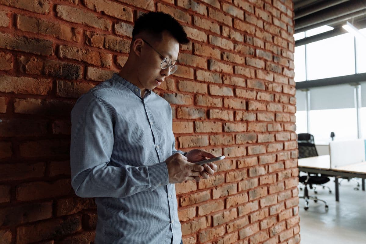 A tradesperson in a business shirt replying to a customer message on a smartphone